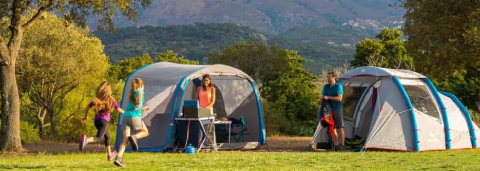 People camping outdoors with two tents set up in a scenic area